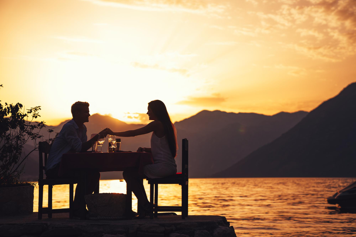A couple sharing dinner beside a mountain lake at sunset